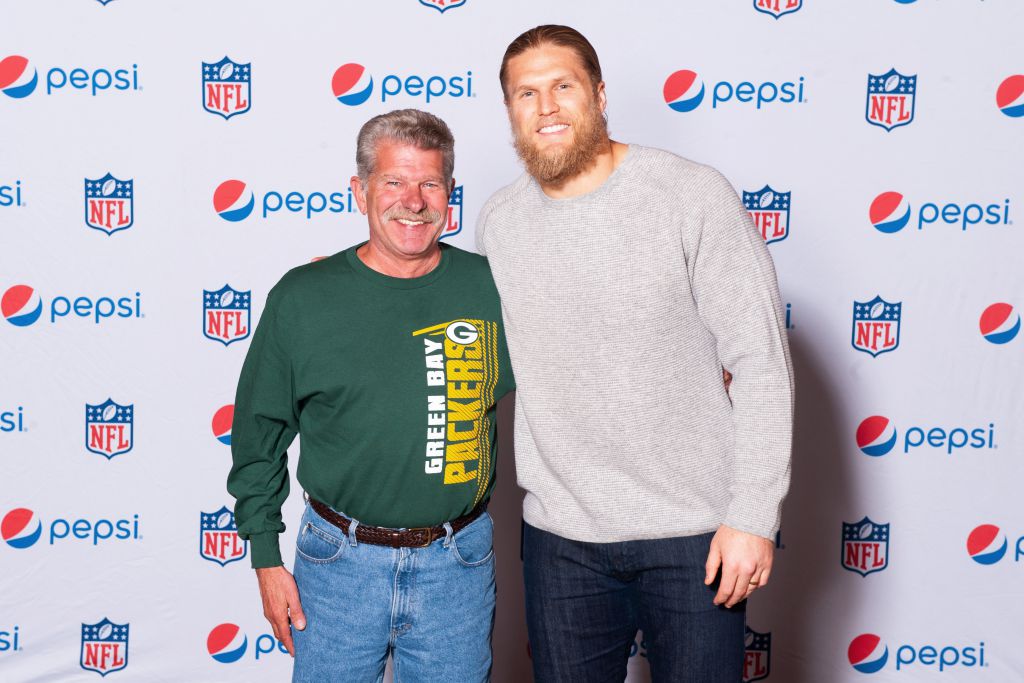 Football star Clay Matthews poses on step repeat with Green Bay Packers fan