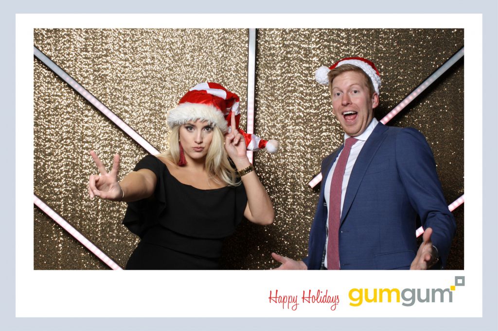 Guests wear santa hat props on gold glitter background Merlo Media holiday party photography